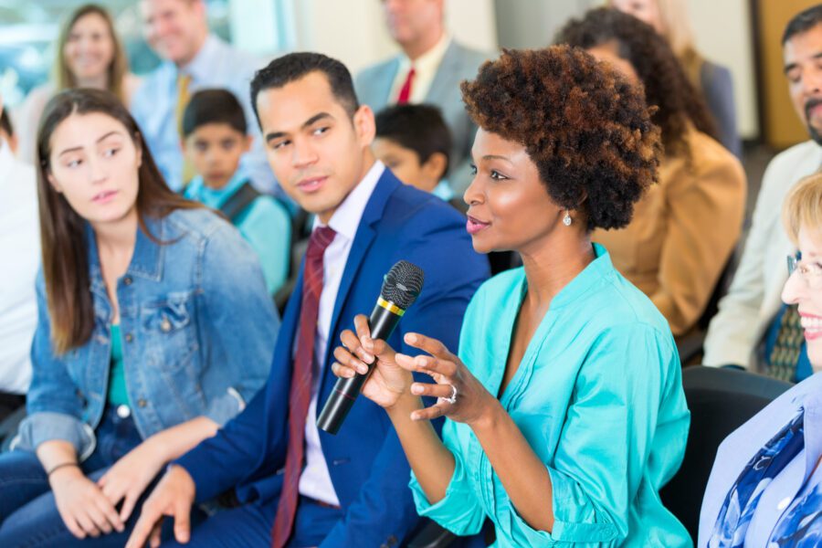 Policy conversation woman with microphone in audience talking