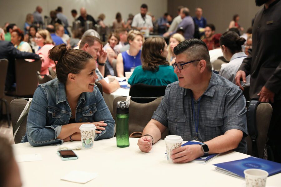 Two people talking at conference man and woman smiling at table