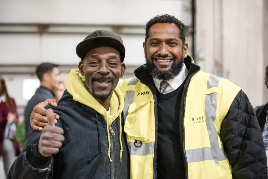 Two men smiling in factory thumbs up