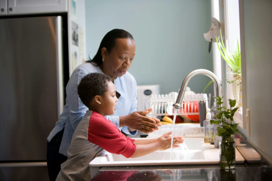 Woman and child washing hands at sink in a kitchen