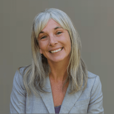 Woman smiling headshot green background gray blazer